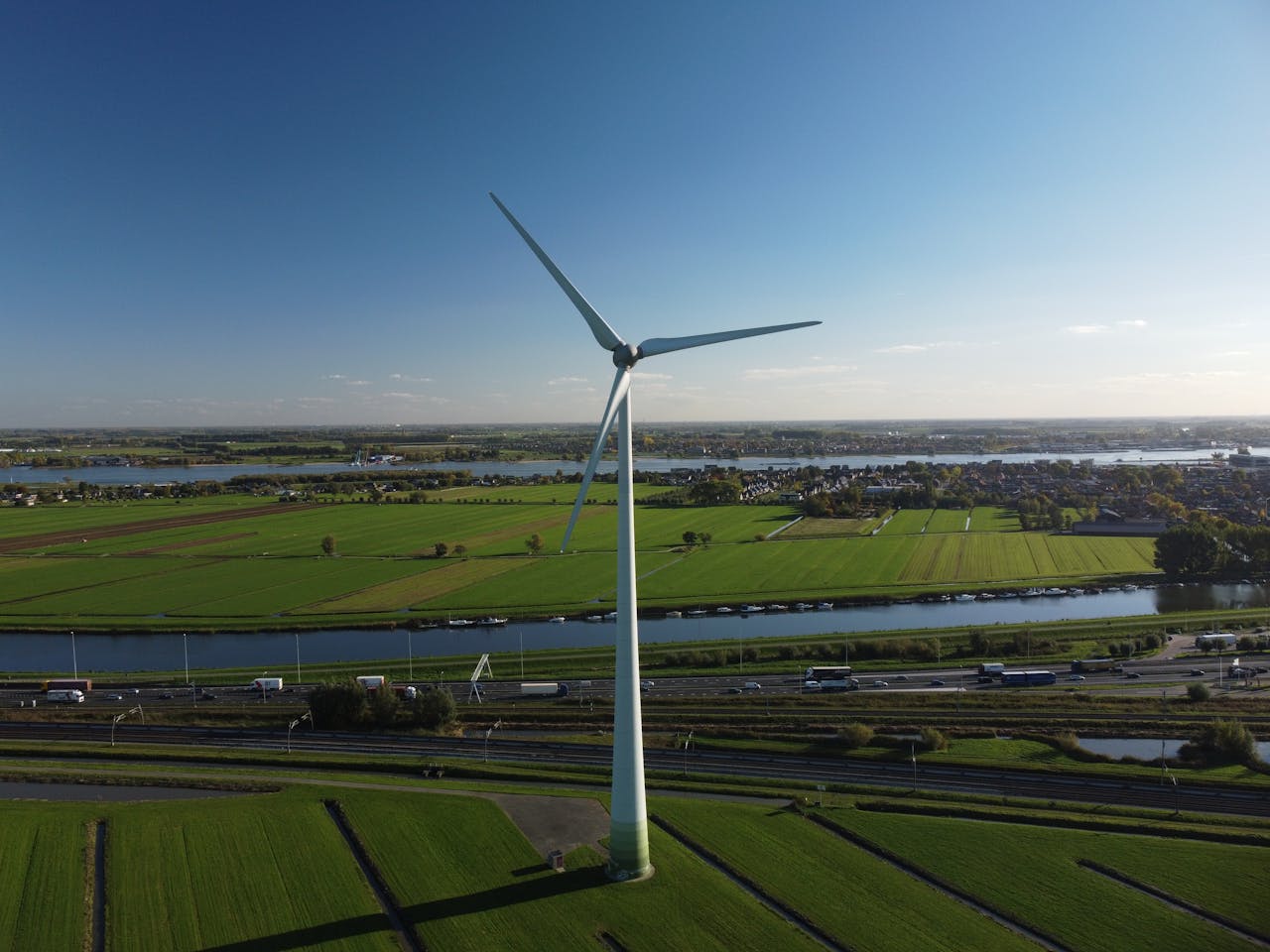 A scenic aerial view featuring a wind turbine in lush green farmland, showcasing renewable energy.